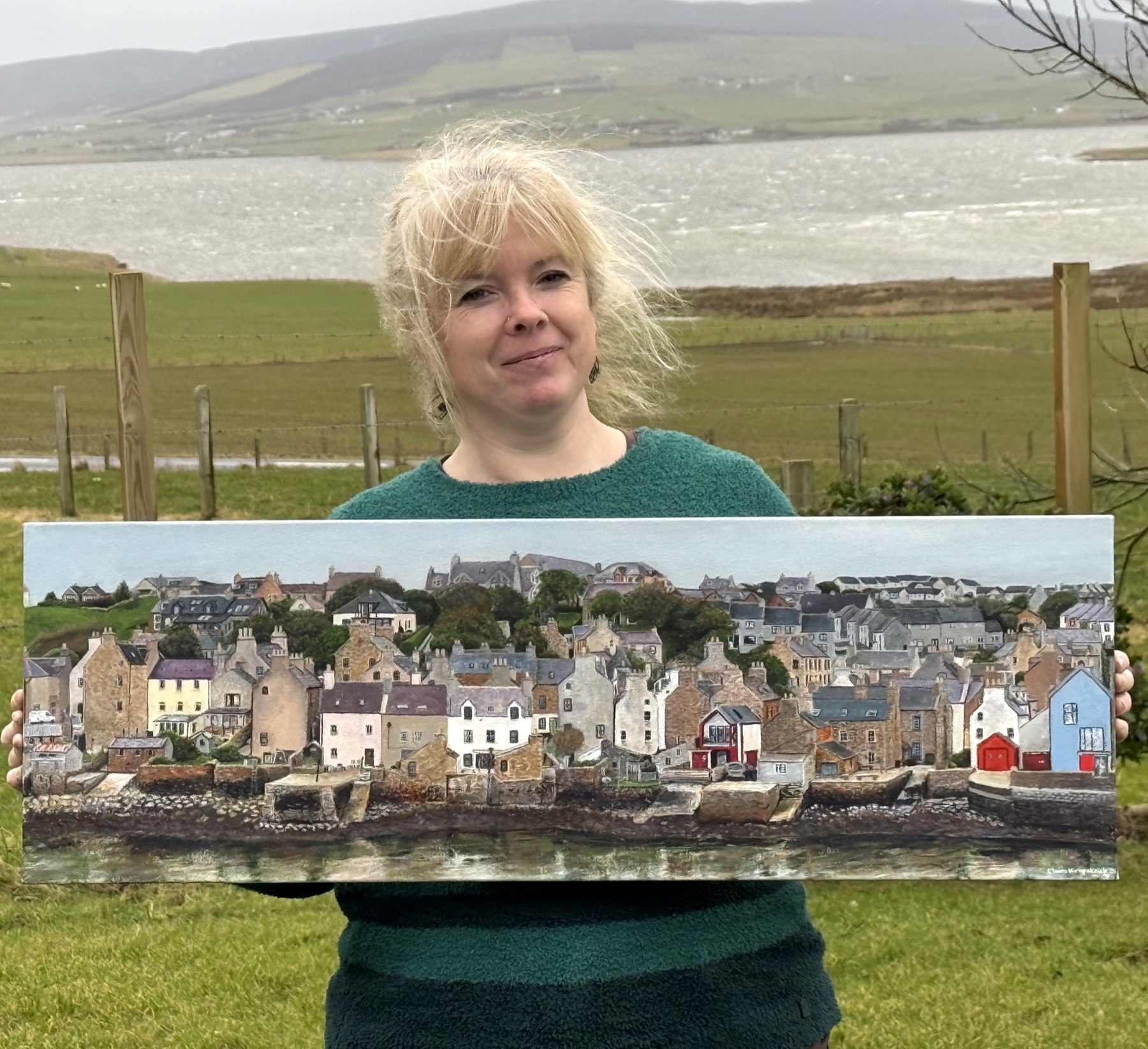 Claire Kirkpatrick holding her panoramic painting of the Stromness waterfront, Orkney